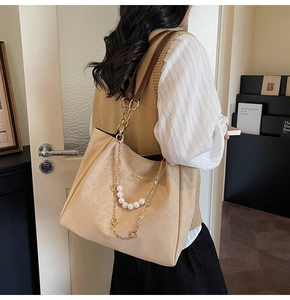Dettaglio borsa shopper beige con tracolla di perle e finiture in metallo oro