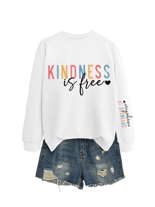Détail du sweat Kindness is Free avec fentes latérales et short en jean déchiré