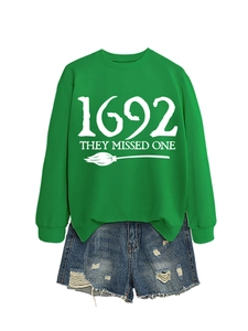 Detail of green Halloween witch sweatshirt with 1692 THEY MISSED ONE text and graphic