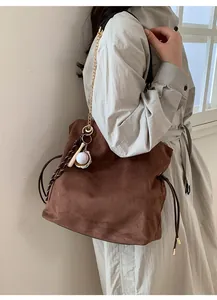 Detail of a brown suede drawstring bag featuring unique baseball themed sports charms