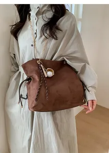 Brown faux suede bucket bag with gold chain strap and unique baseball charm detail