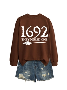 Detail of a brown sweatshirt with 1692 They Missed One print and blue denim shorts