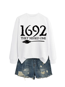Detailed view of white sweatshirt with 1692 text print and ripped denim shorts