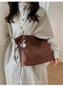 Macro view of dark brown suede tote bag featuring a decorative baseball themed charm