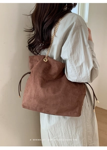 Detail of dark brown suede shoulder bag with fine gold chain and drawstring accents
