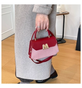 Detail of red and white herringbone small square bag with golden M metal logo