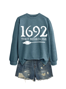 Detail of 1692 They Missed One slogan print on blue crewneck sweatshirt with broom graphic