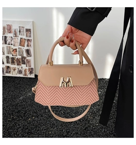 Detail of contrast stitching handbag with fabric texture and gold M logo buckle
