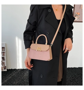 Pink patchwork crossbody bag with gold M buckle worn by model in black coat