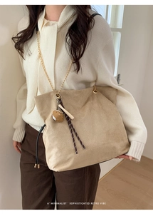 Detail of khaki suede tote bag with golden chain strap and cute cat charm pendant
