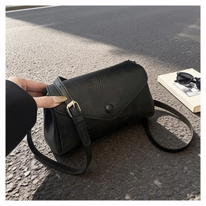 Detail of black vintage textured crossbody bag with envelope flap and adjustable strap
