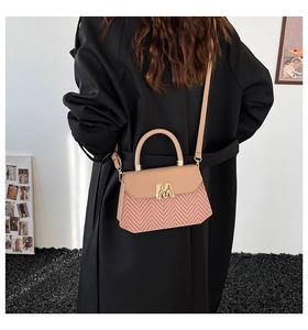 Dettaglio dell'elegante borsa a scatola intrecciata rosa con chiusura dorata a forma di M