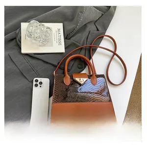 Dettaglio borsa in pelle verniciata marrone con trama serpente e chiusura metallica