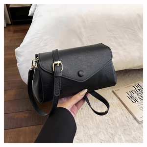 Close-up of black crossbody bag featuring lychee texture leather and gold metal buckles