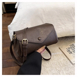Detail of vintage brown pebble faux leather crossbody bag with golden metal buckle