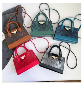 Top view of five faux snakeskin crossbody bags with elegant gold triangular metal buckles