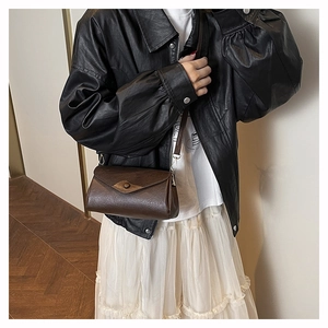 Detail of vintage brown crossbody bag featuring retro round buckle and lychee texture
