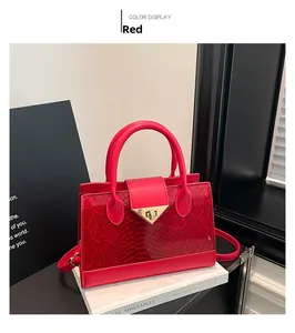 Close-up of red snake-pattern texture and gold metal buckle on leather tote bag