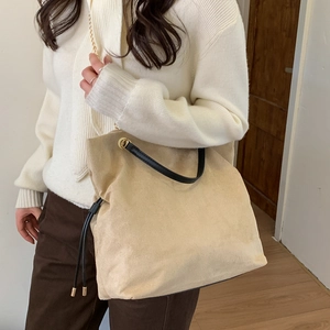 Chic beige tote bag with black straps, shown on a model for a casual winter look