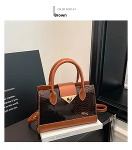 Detail of brown leather handbag with golden triangle lock and snakeskin pattern trim
