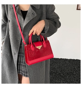 Detail of red crocodile pattern handbag with gold triangle buckle and chain strap