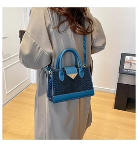 Dettaglio della trama a coccodrillo su borsa blu navy con elegante chiusura in metallo oro