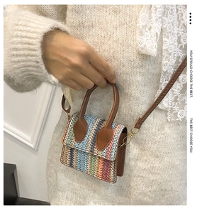 Detail of colorful woven mini crossbody bag with brown leather strap and gold hardware