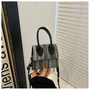 Macro detail of mini woven texture bag featuring black leather handle and metal buckle