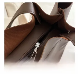 Detail showing smooth silver metal zipper and textured wide fabric shoulder strap of the bag
