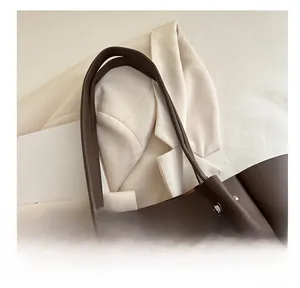 Detail view of dark brown tote bag with slim shoulder straps and metallic stud accents