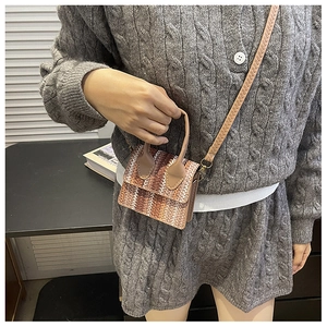 Detail of woven straw mini tote bag featuring beige and brown gradient stripes and straps