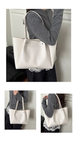 Detail view of large white faux leather tote bag with silver rivet studs and long strap