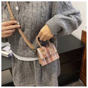 Detail of mini straw crossbody bag with brown faux leather handles and woven texture