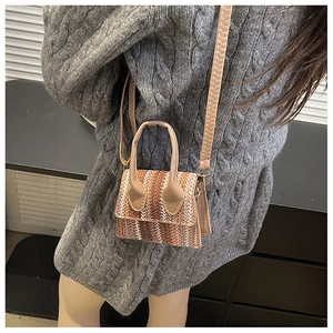 Detail of woven mini bag featuring brown geometric patterns and faux leather shoulder strap