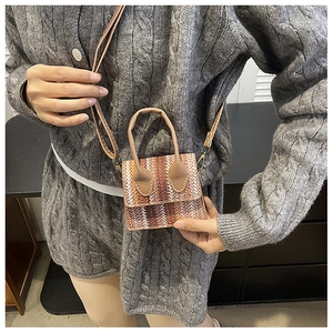 Detail of woven texture on mini brown and beige crossbody bag with dual top handles
