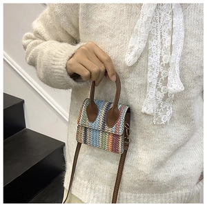 Close-up of a colorful woven mini crossbody bag with dark brown leather handles and strap
