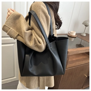 Detail view of large black matte faux leather tote bag with stylish metal rivet accents