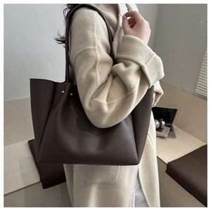 Detail view of large dark brown tote bag with slim shoulder strap and silver rivets
