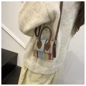 Close-up of rainbow woven straw mini bag with brown leather strap on white sweater