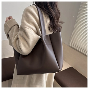Detailed back view of a minimalist large dark brown leather tote bag worn by a model