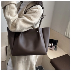 Detail of dark brown tote bag capacity shown with a laptop in a minimalist home setting