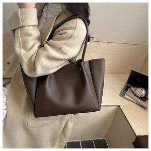 Detail of soft dark brown leather tote bag with silver rivets on the shoulder strap