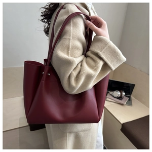 Detail of burgundy tote bag with metallic studs shown on shoulder for office commute