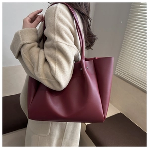 Detail of burgundy large tote bag with silver studs worn with a beige wool coat