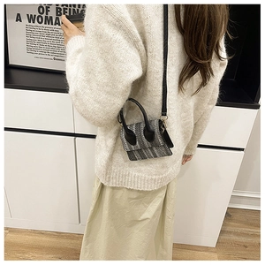 Detailed view of the mini checkered woven crossbody bag styled on a female model