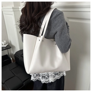 Detail view of large beige tote bag with soft matte finish and silver metal rivets