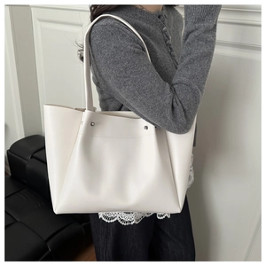 Detailed view of creamy white leather tote bag showing textured surface and metal rivets