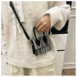 Detail of contrast woven mini handbag featuring gold hardware and black top handles