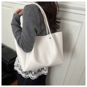 Lifestyle view of a large white matte leather tote bag with pleated details and strap