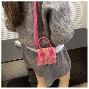 Detail view of fuchsia woven mini bag showing tweed texture and curved top handle